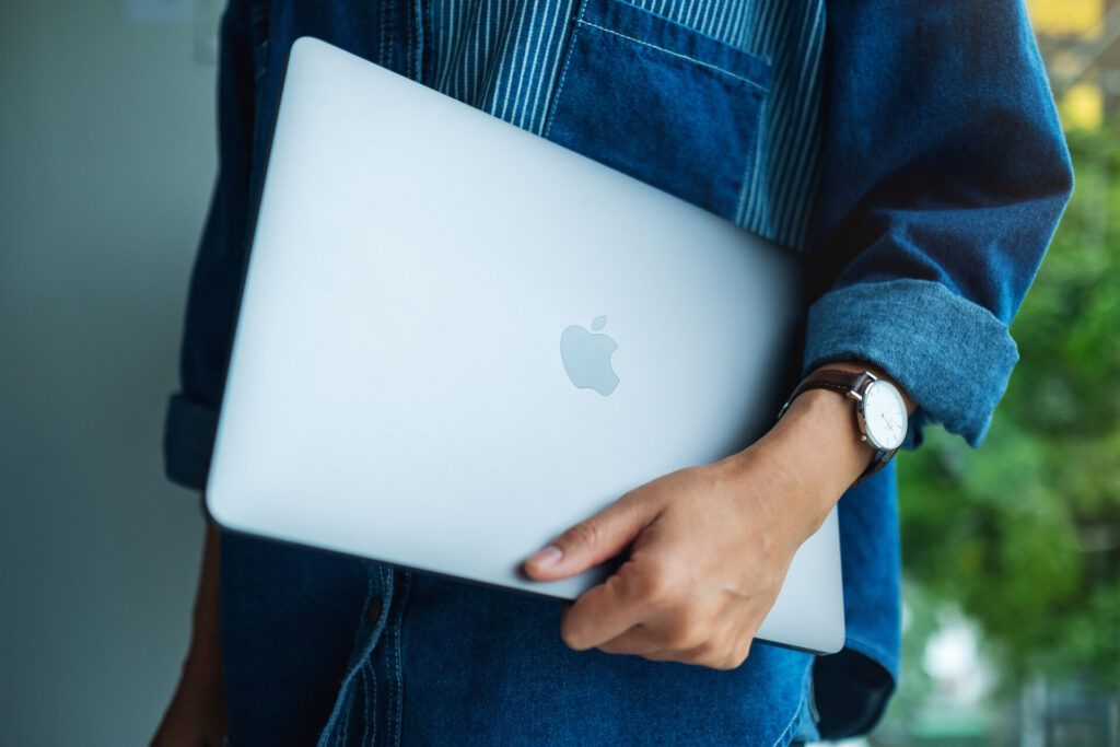 Eine Frau geht spazieren, mit einem Apple MacBook Pro Laptop-Computer in der Hand