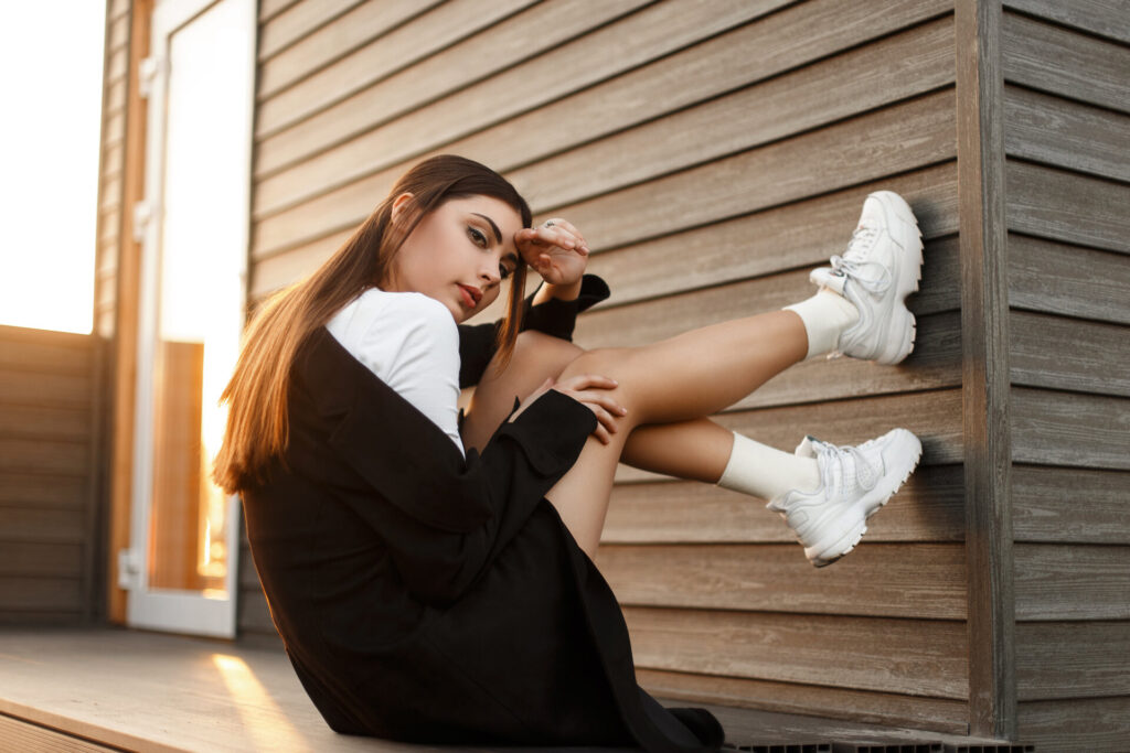 Mädchen mit stylischer Kleidung, lehnt ihre Füße gegen eine Wand