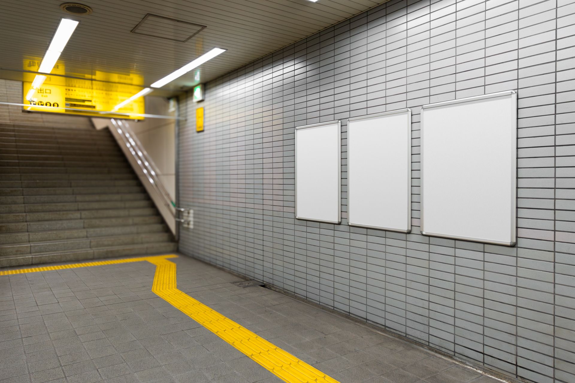 Drei leere Schaukaesten an gefliester Wand in U-Bahn-Unterfuehrung mit gelbem Leitsystem